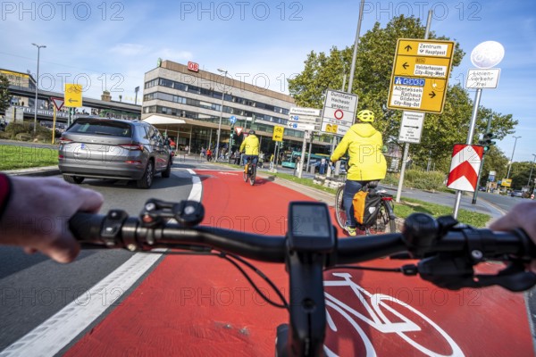 Riding a bike in a bike lane, marked in red to attract the attention of motorists, between 2 lanes, Huyssenallee, in front of Europaplatz, in the city centre of Essen, North Rhine-Westphalia, Germany