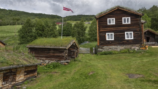 Norwegische Holzhäuser mit Gras auf den Dächern, Fahnenmast mit Norwegen-Flagge, historischer Bauernhof und Pilgerunterkunft Budsjord, Dovre, Pilgerweg Olavsweg oder Olavsleden, Gudbrandsdalen oder Gudbrandstal, Norwegen