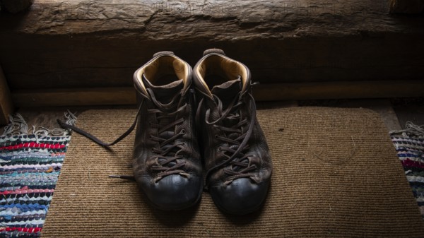 Eingetragene Wanderschuhe auf einem Teppich in einem rustikalen Innenraum, historischer Bauernhof und Pilgerunterkunft Budsjord, Dovre, Pilgerweg Olavsweg oder Olavsleden, Gudbrandsdalen oder Gudbrandstal, Norwegen