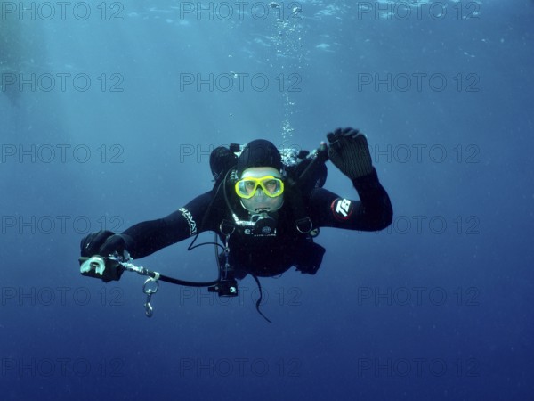 Ein Taucher mit kompletter Tauchausrüstung streckt seinem Tauchpartner, dem offenbar die Luft ausgegangen ist, den zweiten Regler hin, um seine Luft zu teilen. Gleichzeitig reguliert er seine Tarierung. Tauchplatz Wrack der Vis, Pula, Kroatien, Mittelmeer