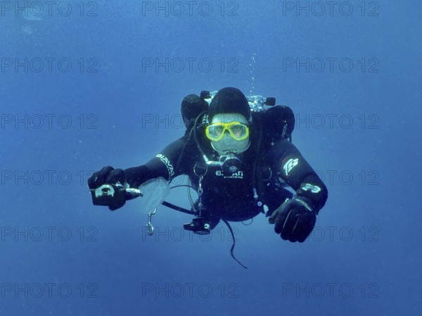 Ein Taucher mit kompletter Tauchausrüstung streckt seinem Tauchpartner, dem offenbar die Luft ausgegangen ist, den zweiten Regler hin, um seine Luft zu teilen. Tauchplatz Wrack der Vis, Pula, Kroatien, Mittelmeer