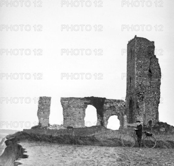 Magic lantern slide of boy with bicycle standing by ruins of All Saints church, Dunwich, Suffolk, England, UK c 1900