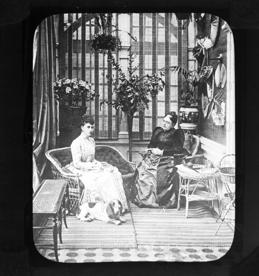A magic lantern slide of Queen Mary, when Princess May of Teck, with her mother, the Duchess of Teck, formerly Princess Mary of Cambridge, indoors in conservatory room, Victorian period, Britain, UK c 1890-1900