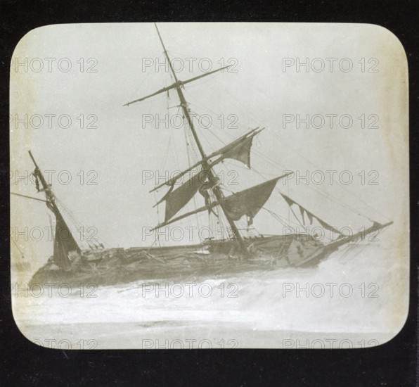 Shipwreck of wooden sailing ship on beach in stormy sea, location unspecified, c 1900