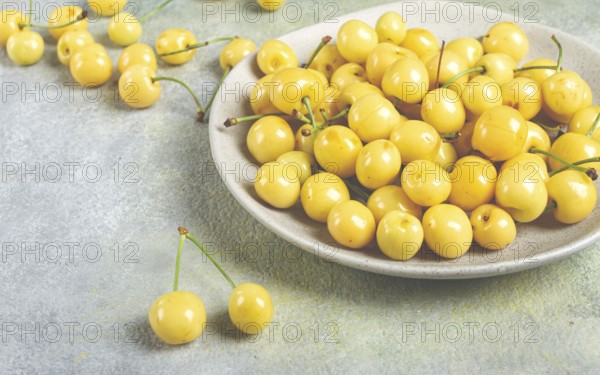 Yellow cherry, cherry berry, scattered on a plate, top view, no people