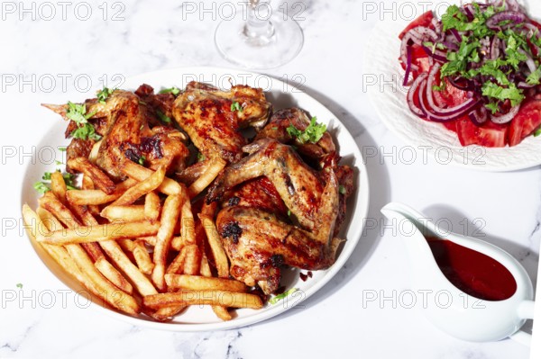 Delicious barbecue chicken wings, with French fries, salad and a refreshing drink, at a cozy table, there are no people