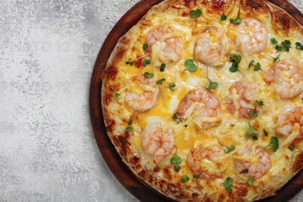 Four cheese pizza with shrimp and fresh microgreens, served on a wooden board, homemade, no people