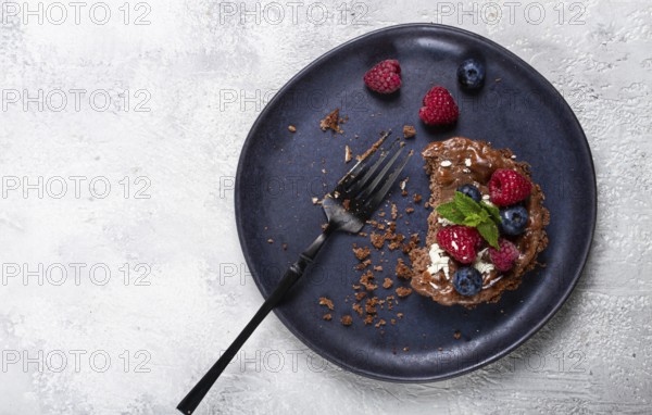Half-eaten chocolate tartlet, on a plate, stuffed with cottage cheese and berries, breakfast, homemade, no people