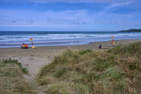 Rettungsflaggen am Strand mit grasbewachsenen Dünen und leichten Wellen im Meer, Kaka Point, Clutha District, Otago, Südinsel, Neuseeland