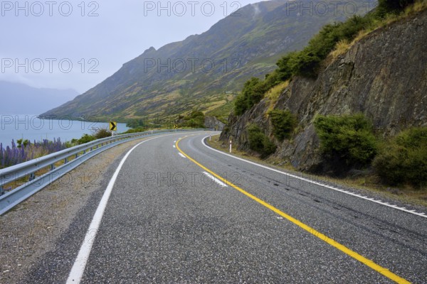 Kurvige Küstenstraße entlang von Felsen mit Blick auf den See, Lake Wanaka, The Neck, Otago, Südinsel, Neuseeland
