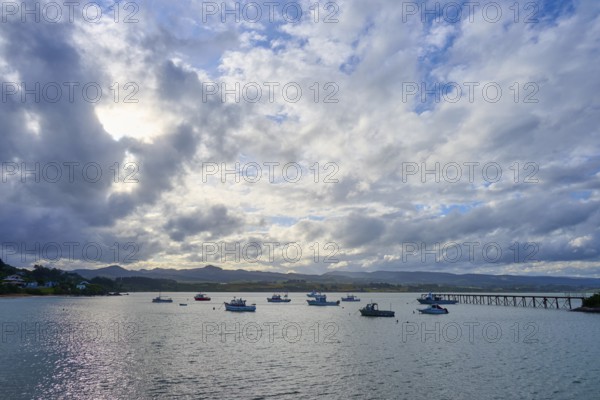 Boote auf ruhigem Wasser unter einem bewölkten Himmel bei Sonnenuntergang, Moeraki, Hampden, North Otago, Südinsel, Neuseeland