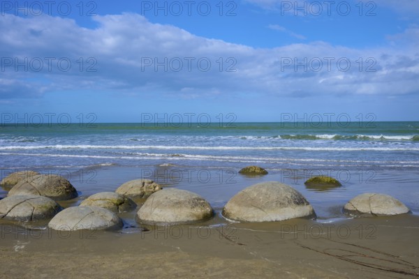 Mehrere runde Felsen an einem Sandstrand mit Blick auf das Meer und bewölkten Himmel, Moeraki Boulders, Moeraki, Hampden, North Otago, Südinsel, Neuseeland