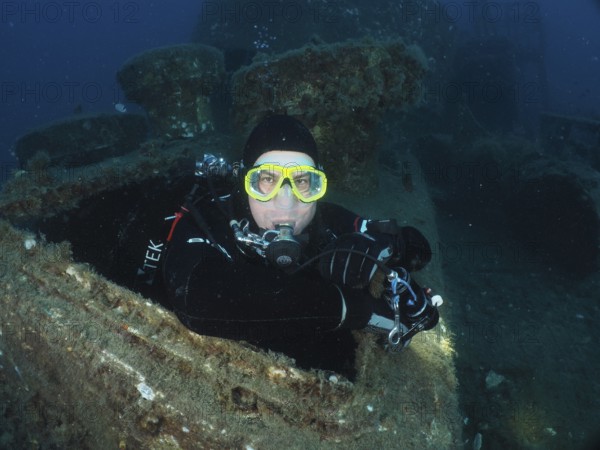 Diver looking out of the hatch of a wreck. Dive site wreck of the Vis, Pula, Croatia, Mediterranean Sea