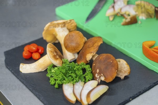 Various mushrooms and herbs on a black plate
