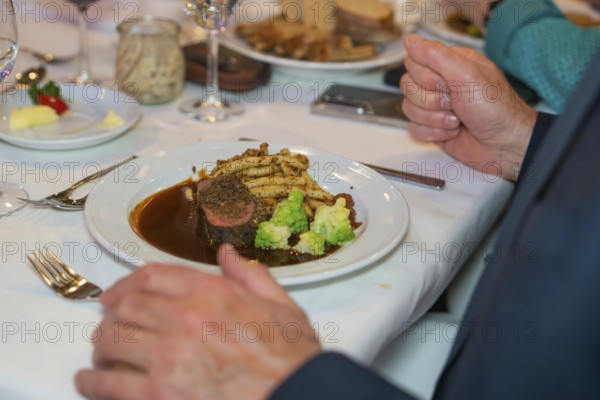 Steak with vegetables and chips, presented on a festively laid table with a white tablecloth