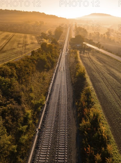 Train tracks run through fields and trees in the light of the sunrise, Hermann Hesse railway, Ostelsheim, Black Forest, Germany