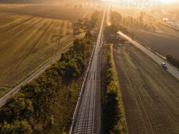View of railway tracks and neighbouring fields at sunrise in golden light, Hermann Hesse Railway, Ostelsheim, Black Forest, Germany