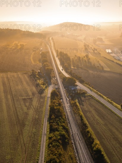 Rural scene with tracks and fields in the light of the rising sun, Hermann Hesse railway, Ostelsheim, Black Forest, Germany