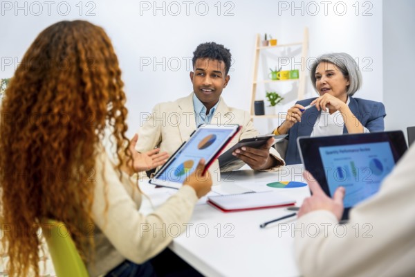 Business professionals discussing financial data and charts on digital tablets and paper during a corporate meeting in a modern office, fostering collaboration and teamwork
