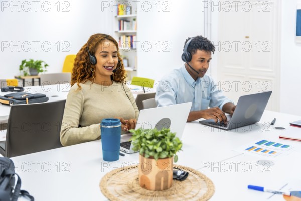 Customer service representatives wearing headsets and working on laptops, connecting with clients and offering professional online support in a modern office environment