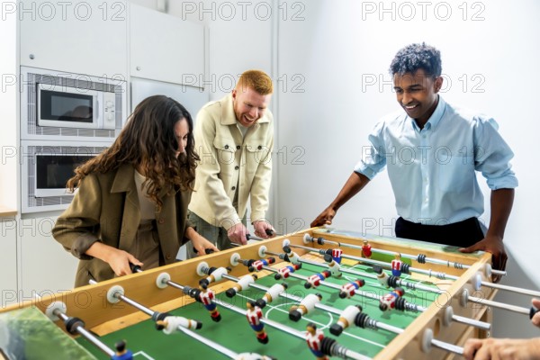 Diverse coworkers enjoying a friendly foosball game during a work break, fostering teamwork, camaraderie, and a positive office environment in a modern workplace