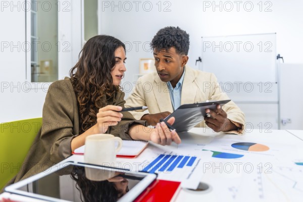 Diverse business colleagues discussing financial data and charts during an office meeting, collaborating on a project and analyzing performance figures for strategy development