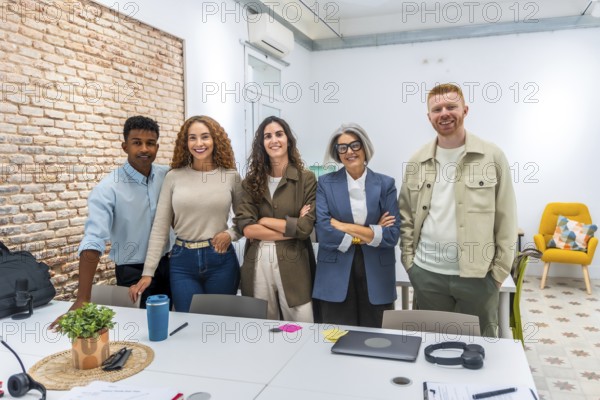 Group of multi ethnic business people posing together in a bright, contemporary office space, symbolizing teamwork, collaboration, and professional success