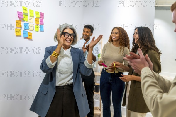 Diverse business team clapping hands, celebrating a successful achievement or project in a modern office, showing teamwork, support, and positive collaboration after a brainstorming session