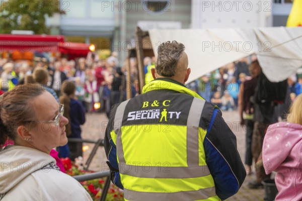 A security guard monitors the event amidst a crowd of visitors at the city festival, Feuernacht, Sindelfingen, Germany