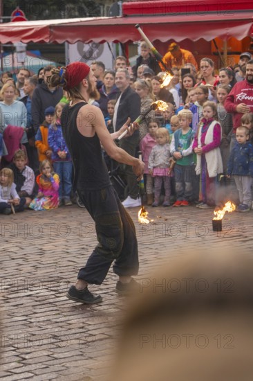 A fire-breather juggles in front of a colourful audience at a festival, Feuernacht, Sindelfingen, Germany