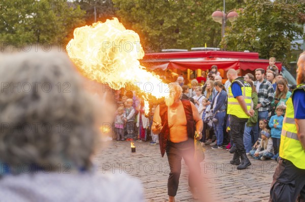 A fire-eater performs an exciting show in front of a large audience on a cobbled street, Feuernacht, Sindelfingen, Germany