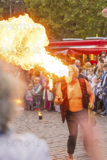 A man breathes fire during a show, surrounded by an attentive audience at a festival, Feuernacht, Sindelfingen, Germany