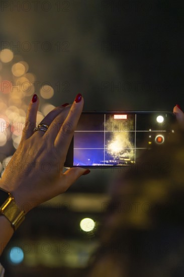 A hand with a mobile phone holds the fireworks in the night, sparkling bokeh, Fire Night, Sindelfingen, Germany
