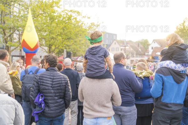 People gather under trees in sunny weather with colourful decorations in the background, Fire Night, Sindelfingen, Germany