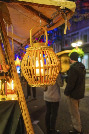 A warm lantern illuminates a night market stall, people stand in the background, Feuernacht, Sindelfingen, Germany