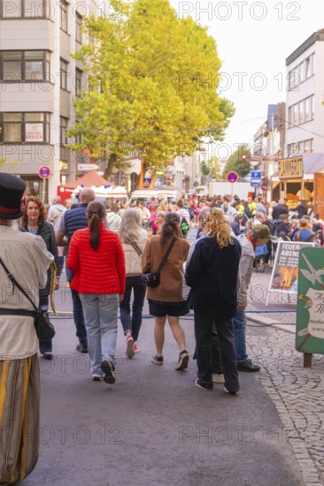 Many people stroll through a busy street at a city festival, trees and colourful clothes characterise the picture, Fire Night, Sindelfingen, Germany