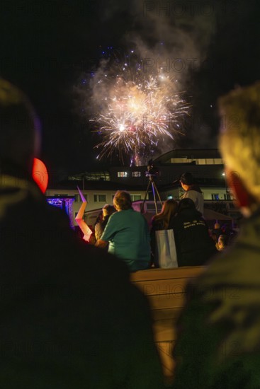 Group of spectators watching fireworks in the night sky above a building, Fire Night, Sindelfingen, Germany