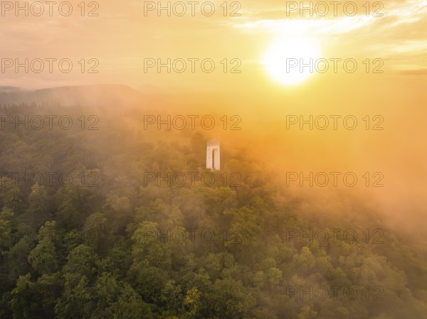 A lone tower rises out of a misty forest, illuminated by a warm sunset, Schönbergturm, Pfullingen, Swabian Alb, Germany
