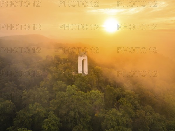 Foggy morning with tower surrounded by trees as the sun rises, Schönberg Tower, Pfullingen, Swabian Alb, Germany