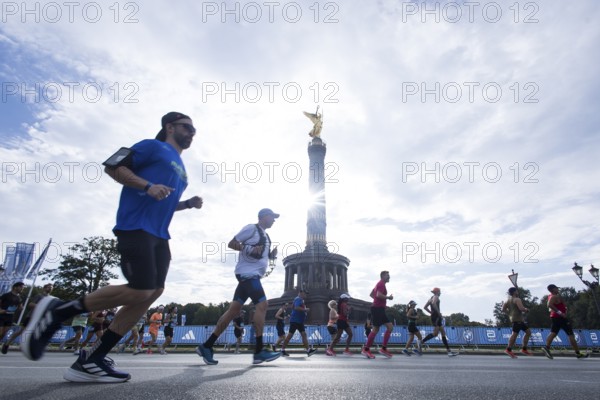 Runners run around the Victory Column against the backlight of the sun on the Great Star at the 51st BMW Berlin Marathon 2025 on 21 September 2025