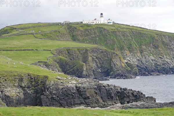 Lighthouse on a grassy cliff overlooking the sea under a cloudy sky, Sumburgh Head, Shetland Islands, Scotland, United Kingdom