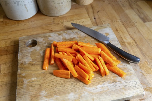 Sliced carrots on wooden chopping board with knife