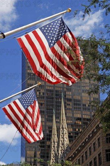 Waving USA flags, behind towers of St Patrick's Cathedral, Manhattan, New York City, USA
