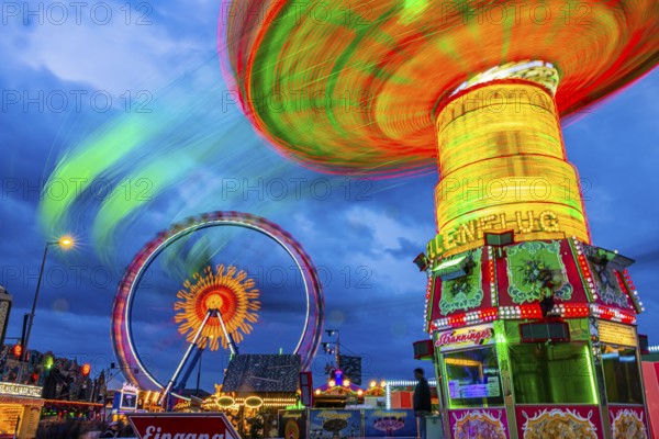Illuminated chain carousel in motion, behind the Ferris wheel in motion, Festwiese, Theresienwiese, Oktoberfest, Munich, Upper Bavaria, Bavaria, Germany