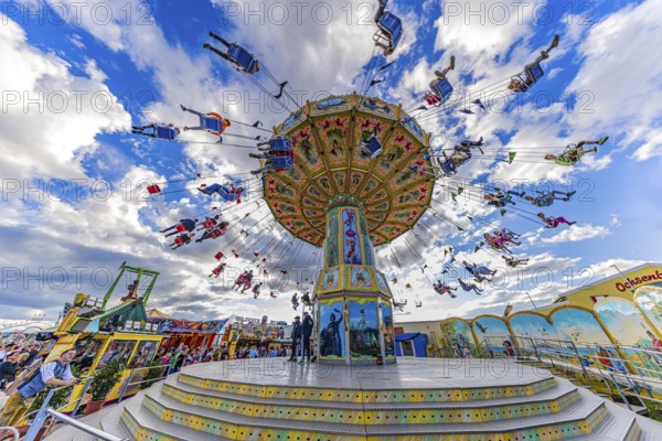 Chain carousel in motion in front of a white-blue sky, Theresienwiese, Oktoberfest, Munich, Upper Bavaria, Bavaria, Germany