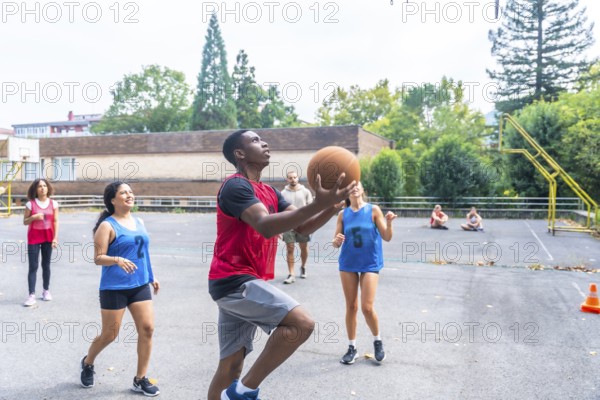 Group of diverse basketball players enjoying a lively game on an outdoor court, highlighting teamwork, athleticism, and the pure joy of engaging in sports with friends