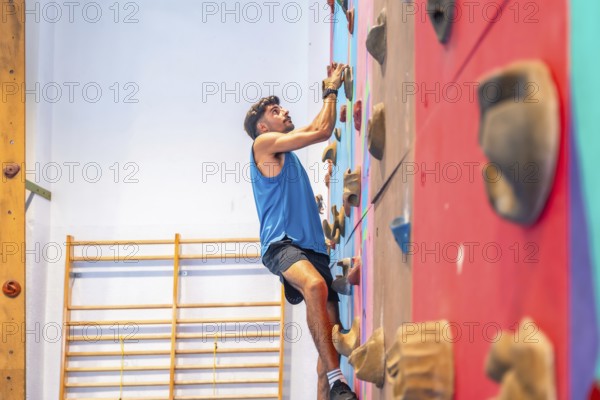 Young sportsman ascending a vibrant climbing wall, showcasing strength, agility, and intense focus while striving to achieve fitness goals and personal growth in an indoor climbing gym