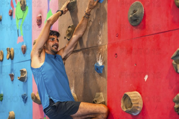 Focused male athlete ascends a vibrant indoor climbing wall, demonstrating strength, agility, and determination in his pursuit of physical and mental fitness