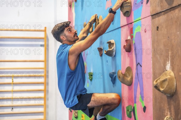 Young male athlete ascending an indoor climbing wall, demonstrating strength, agility, and focus in his pursuit of physical fitness and the thrill of climbing