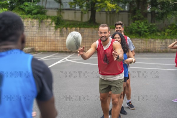Group of athletes passing a rugby ball during a training session on an urban basketball court, practicing their skills and teamwork for an upcoming match